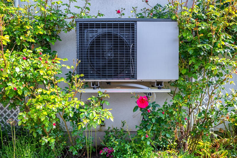 Air source heat pump next to flowers