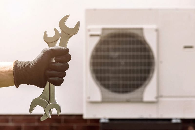Holding spanners next to an air source heat pump