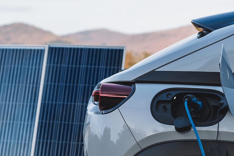 Charing electric car next to solar panels